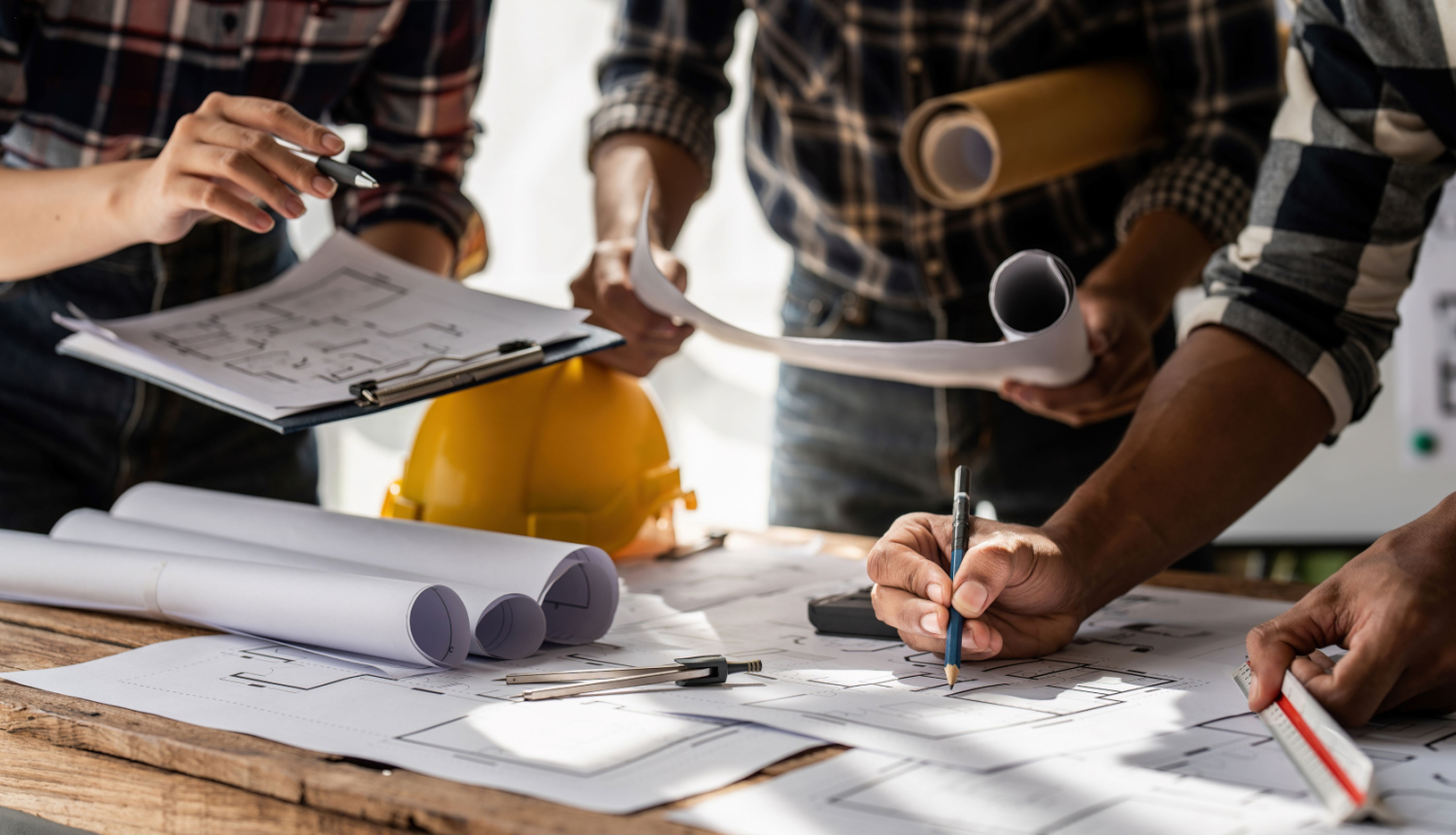 Grupa ar būniekiem spriež par rasējumiem, kas atrodas uz galda