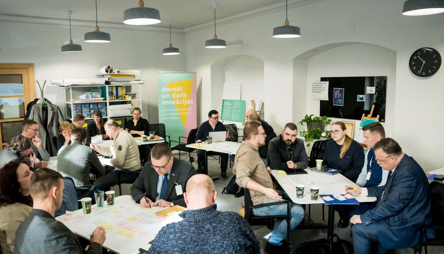 Inovācijas sprints - cilvēki sēž pie galdiņiem, sarunājas