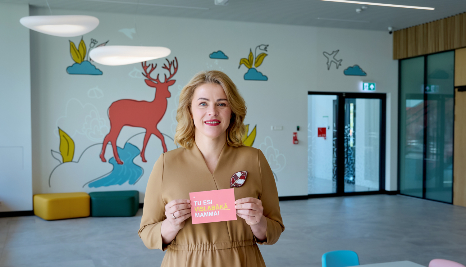 Ministru prezidente Evika Siliņa tur rokās kartīti ar uzrakstu "Tu esi vislabākā mamma!"