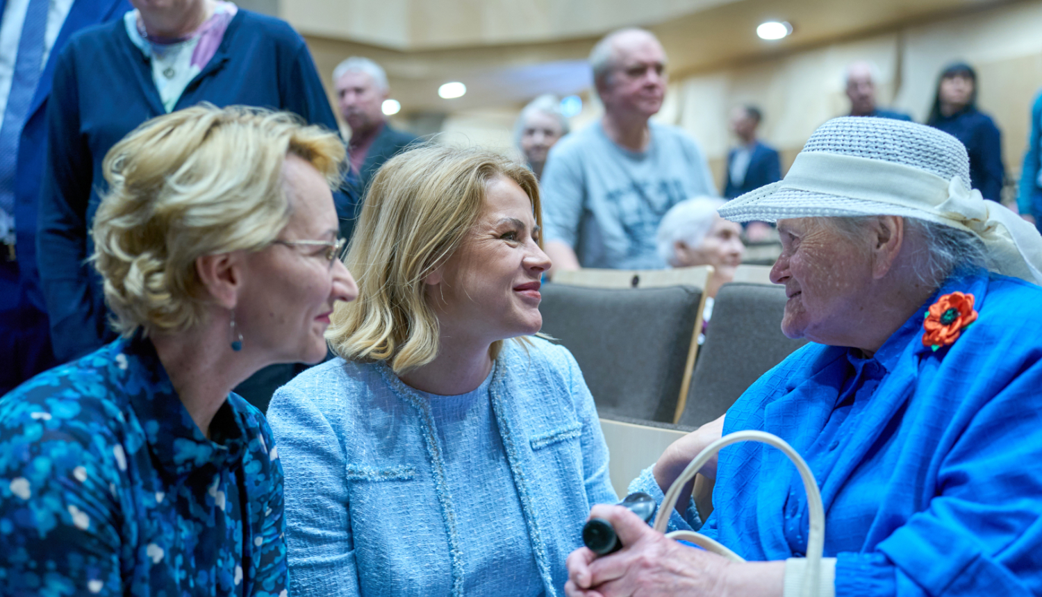 Ministru prezidente Evika Siliņa sarunā ar Latvijas simtgadnieku salidojuma dalībnieci, Ministru prezidentei kreisajā pusē Izglītības un zinātnes ministre Dace Melbārde