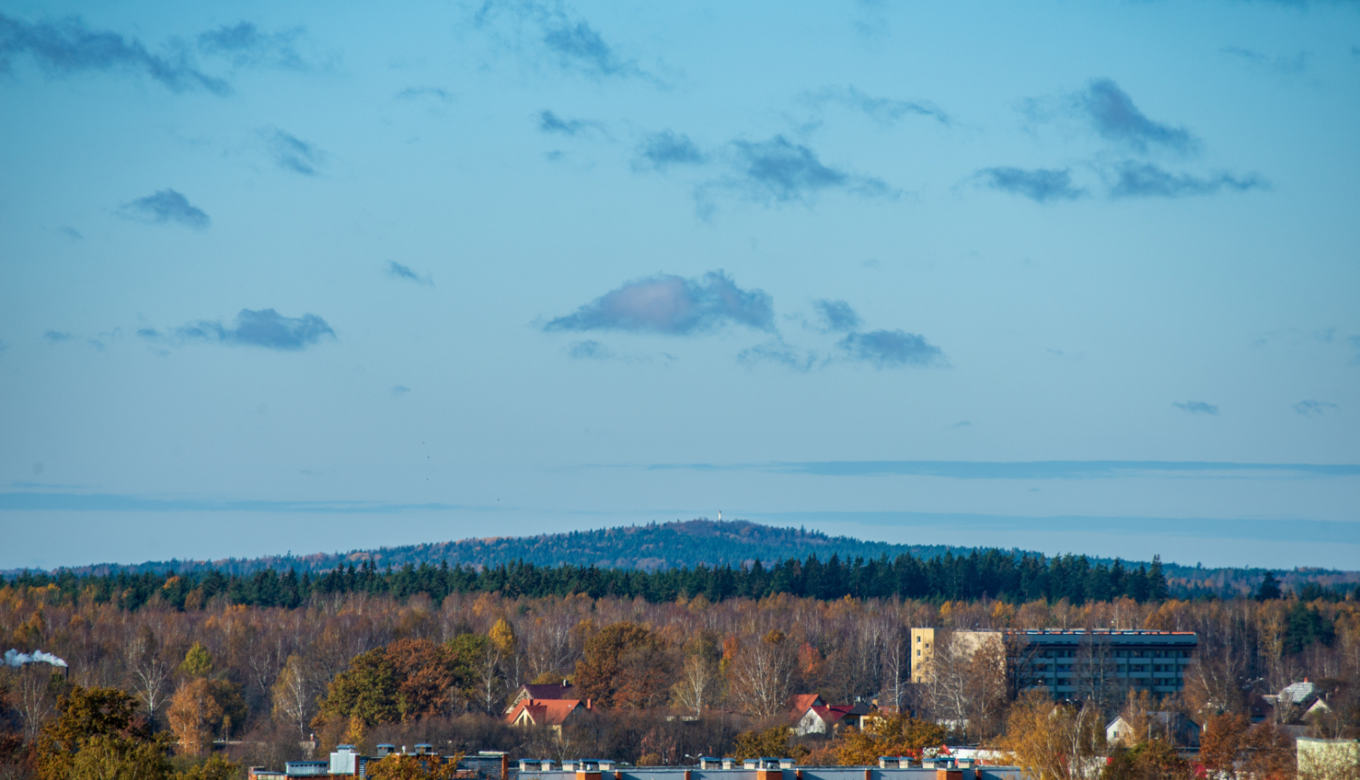 Skats uz pilsētu un tālumā esošu mežu un pakalnu
