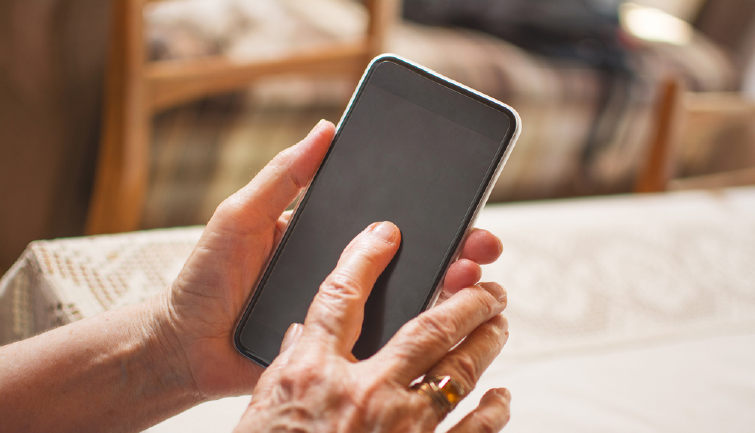 Cilvēks tur rokās mobilo telefonu
