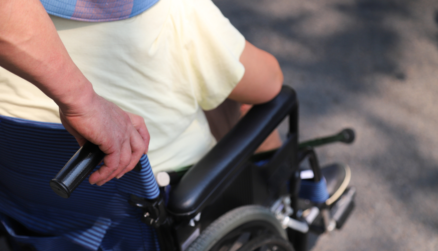 Asistents stumj cilvēku ratiņkrēslā