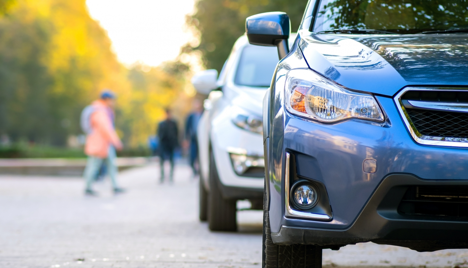 2 auto uz ielas. Fonā koki, cilvēki