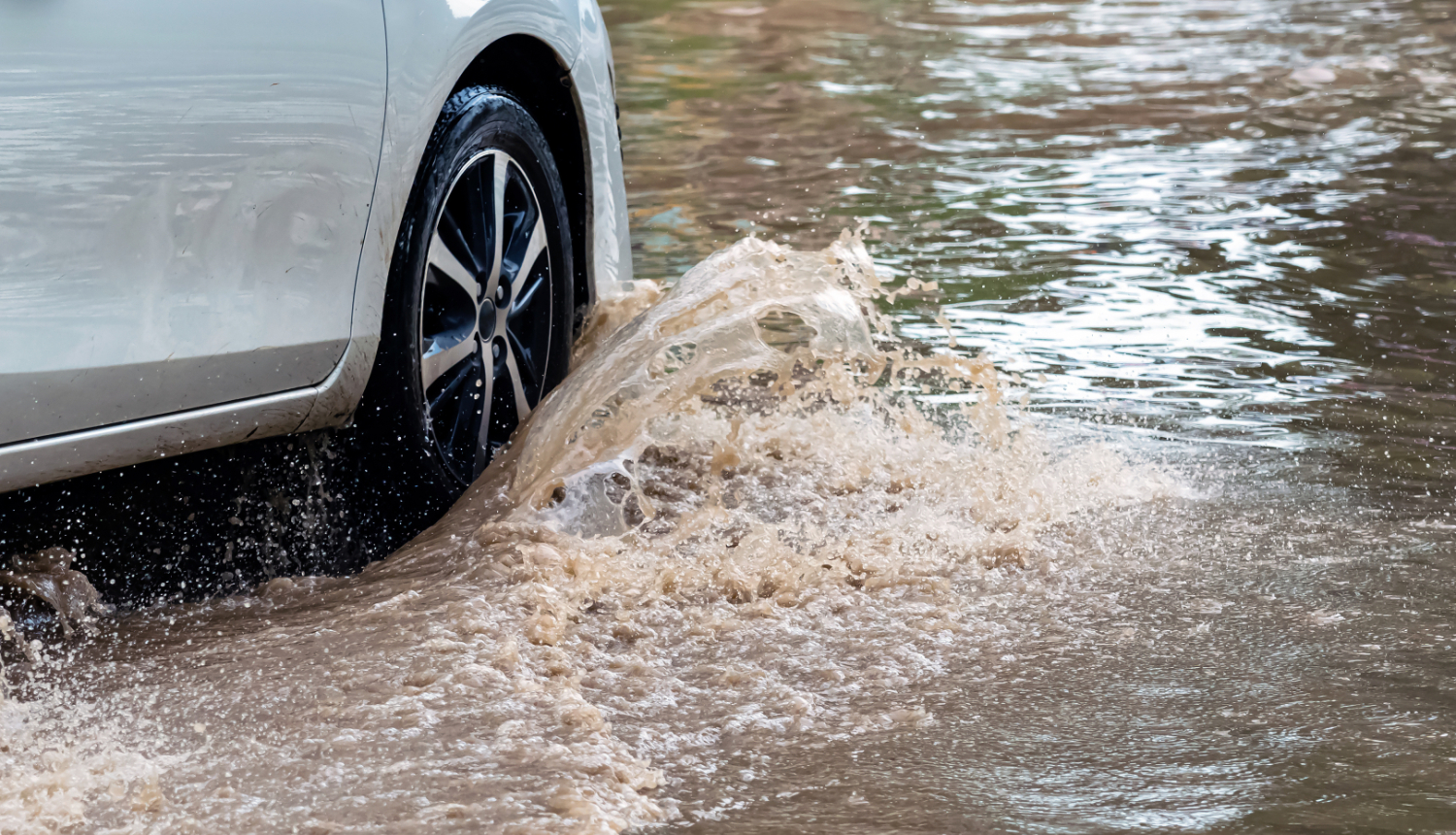 Automašīna brauc cauri dziļai peļķei