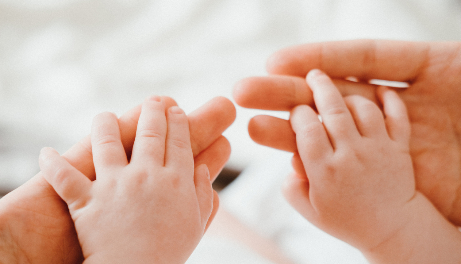 Mazulis ar abām rokām pieķēries vecāka rokām