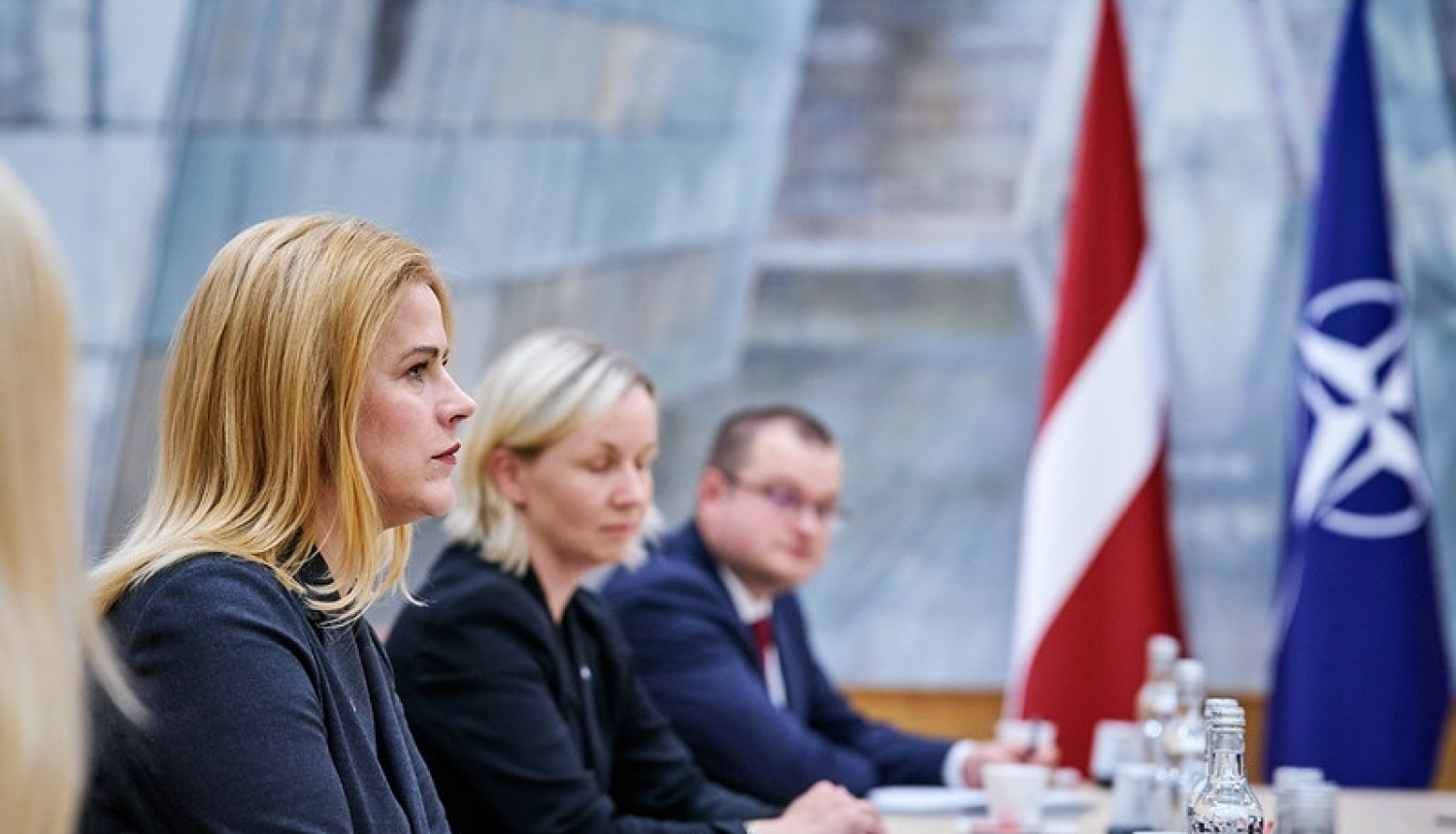Ministru prezidente Evika Siliņa tikšanās laikā ar NATO amatpersonām. Fonā redzami Latvijas un NATO karogi