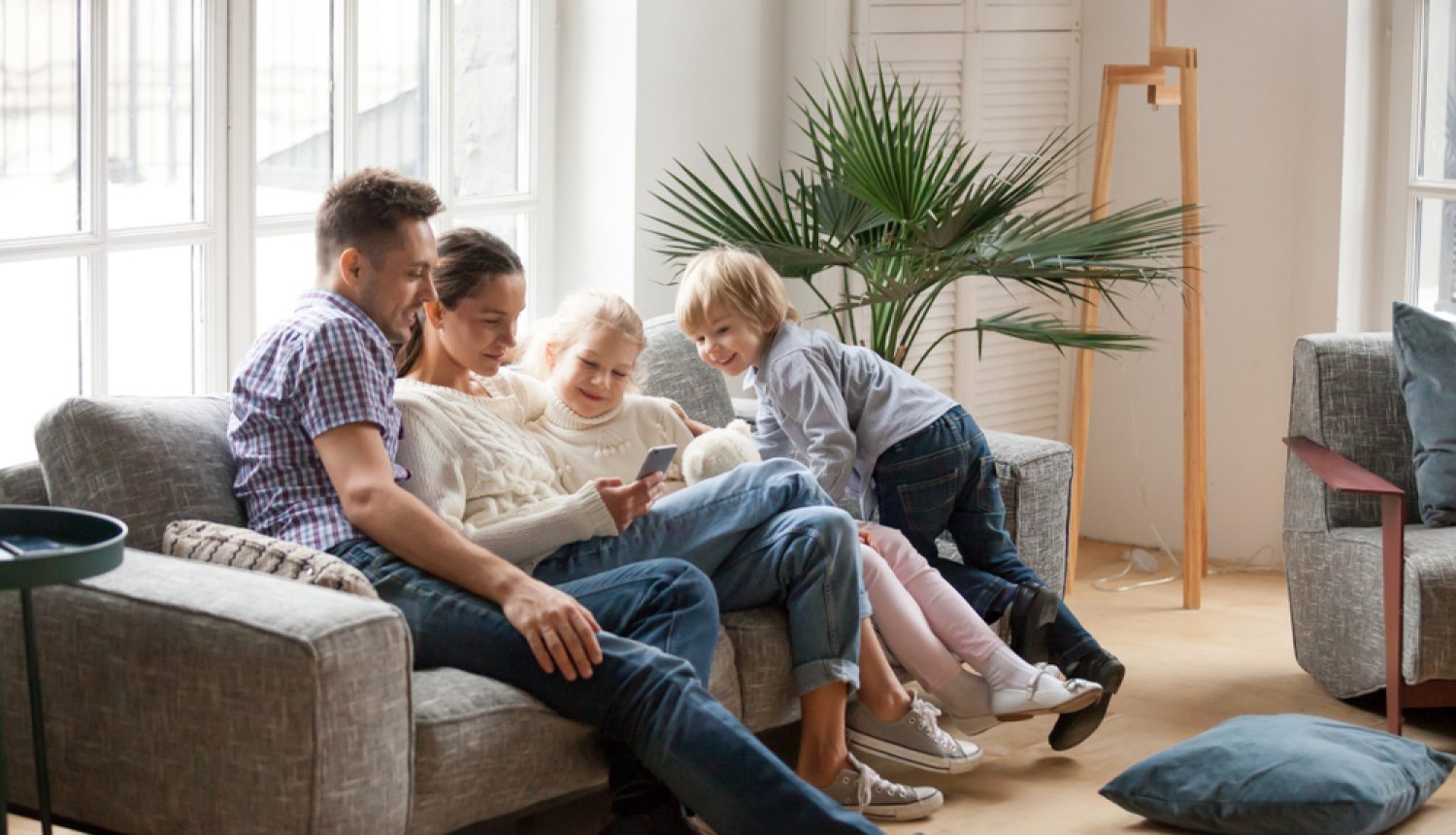Ģimene jaunā mājoklī uz dīvāna. Mamma, tētis un 2 bērni. 