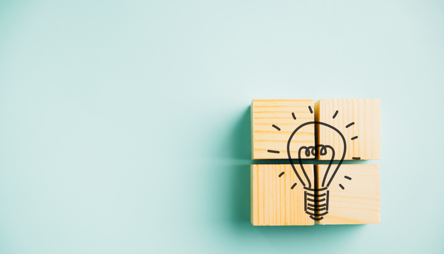 Četri kopā salikti koka klucīši izveido spuldzītes attēlu, kas simbolizē ideju