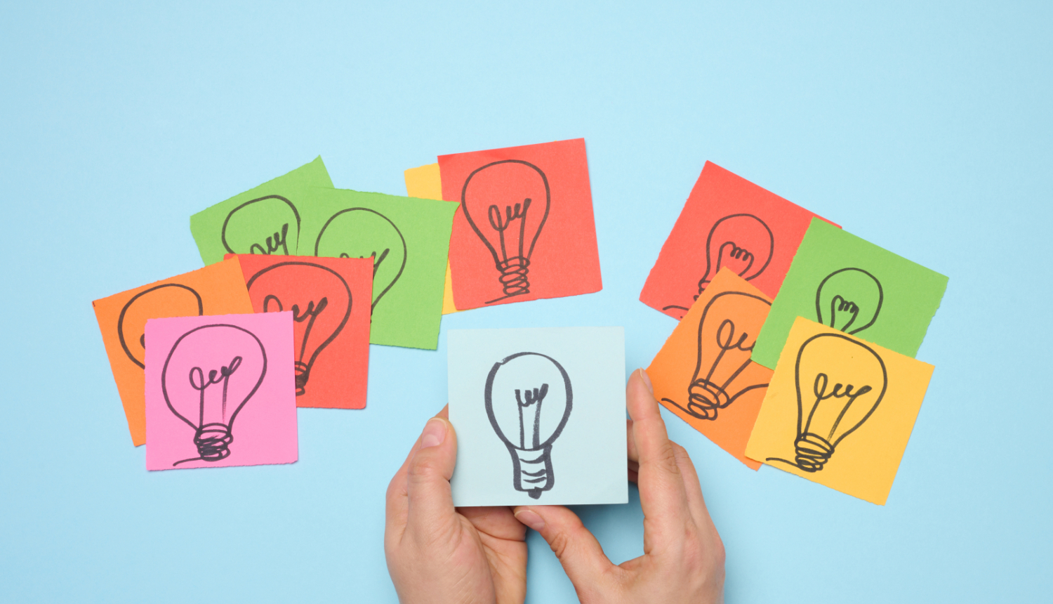 Uz dažādu krāsu papīra lapiņām uzzīmētas spuldzītes