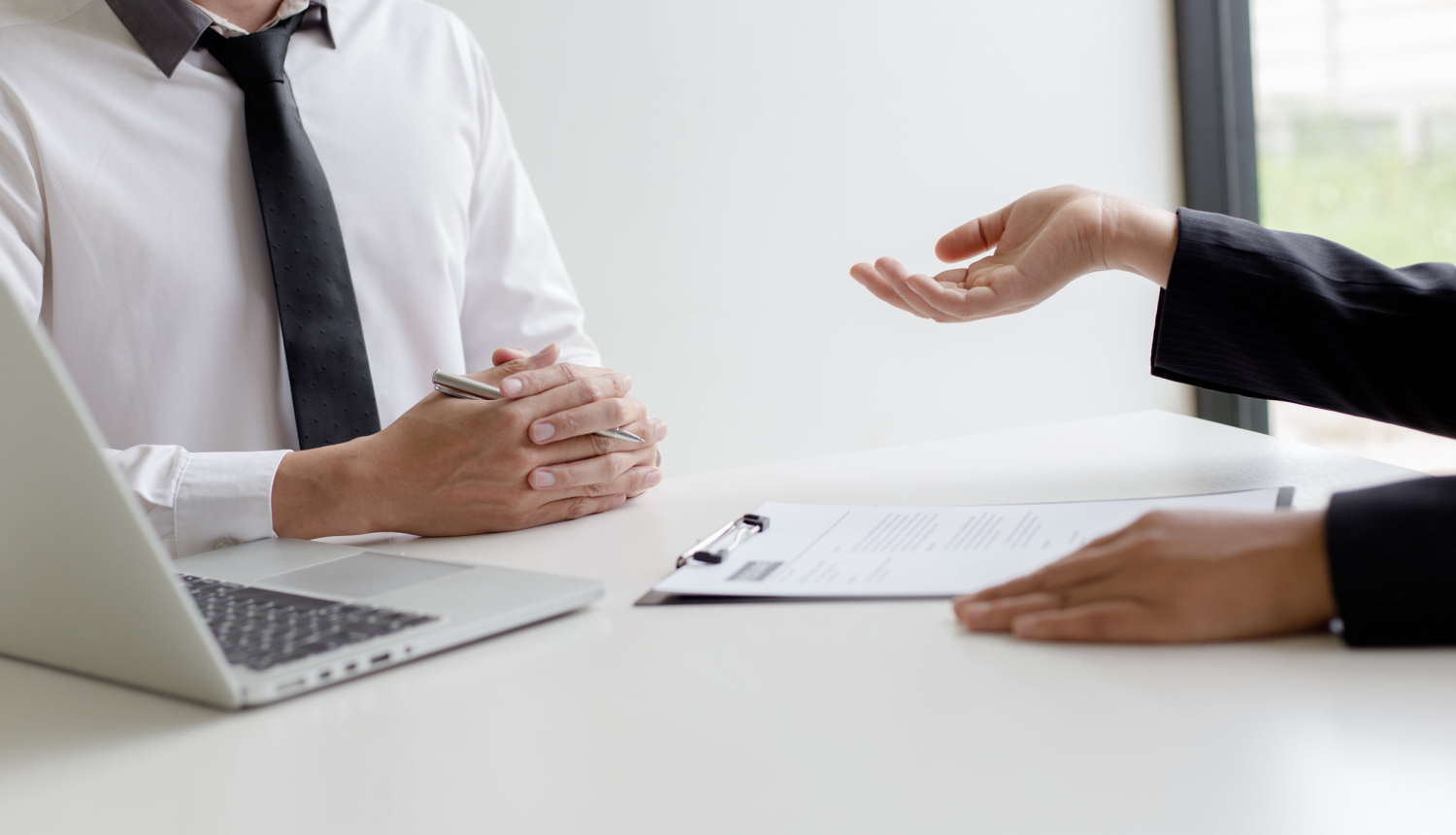 Cilvēki sarunājas pie datora katrs savā galda pusē