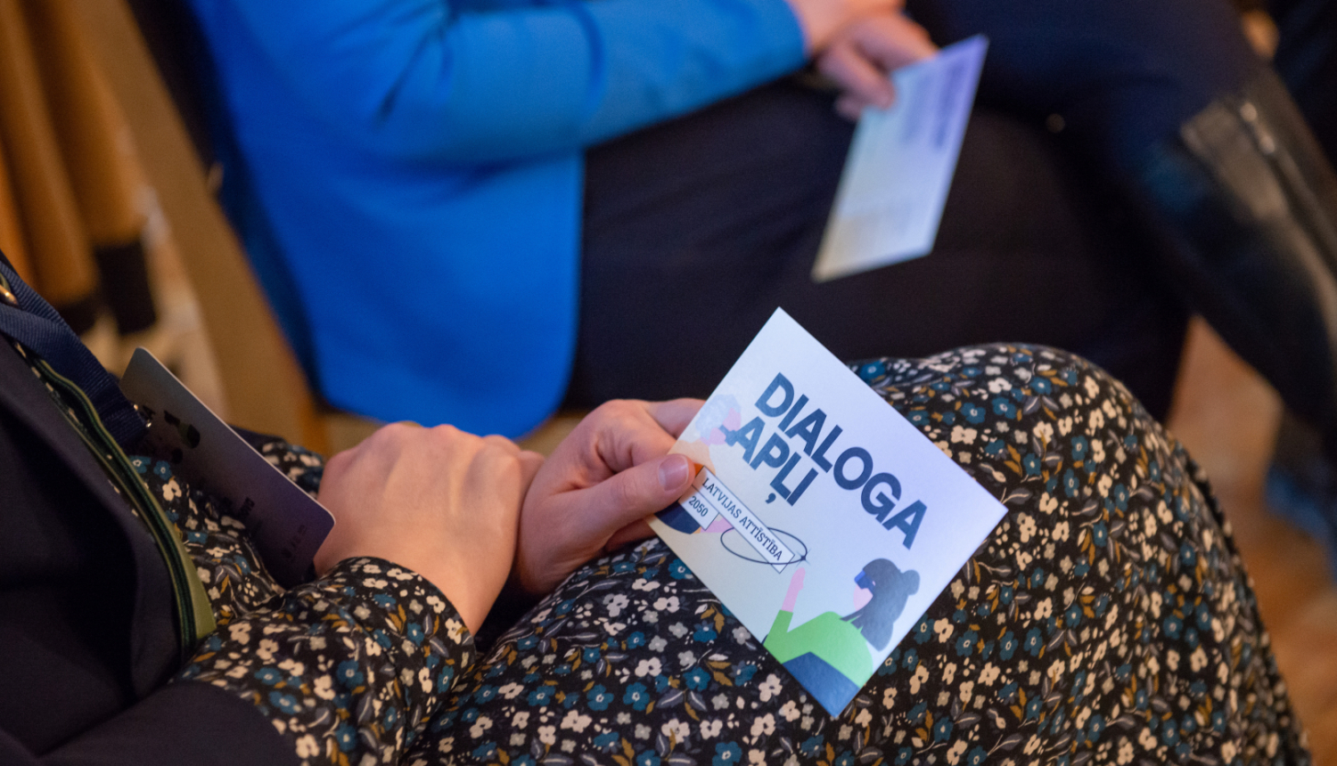 Sieviete rokā tur kartīti ar uzrakstu Dialoga apļi