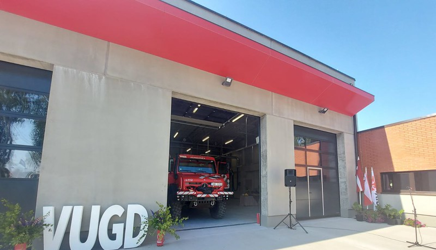 Fotogrāfija, kurā redzams Katastrofu pārvaldības centrs, ugunsdzēsēju auto un lieli burti VUGD.