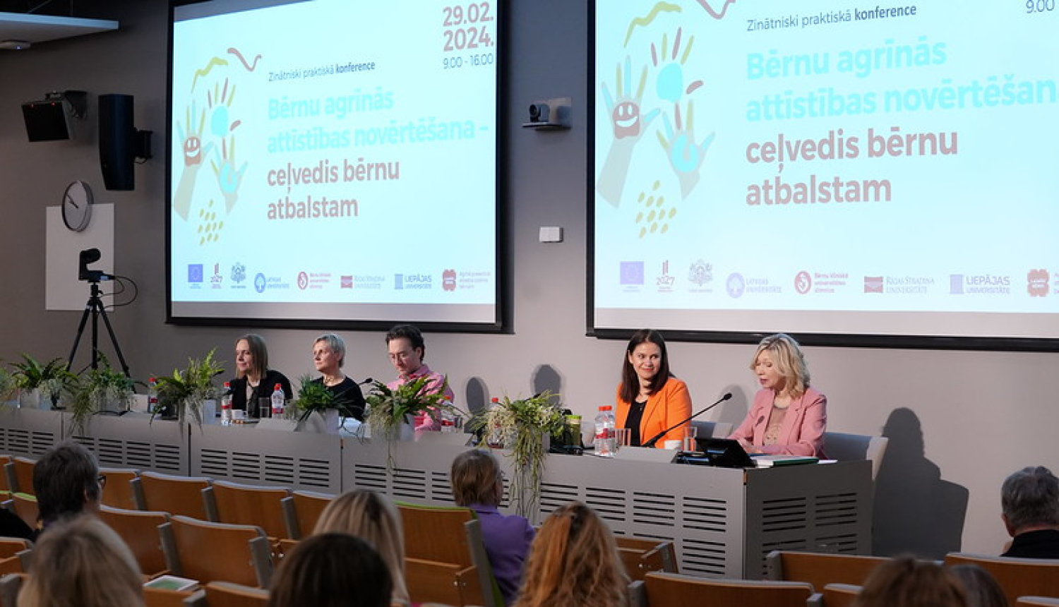 Foto no Zinātniski praktiskās Konferences "Bērnu agrīnās attīstības novērtēšana - ceļvedis bērnu atbalstam". Konferences dalībnieki sēž pie galda. 