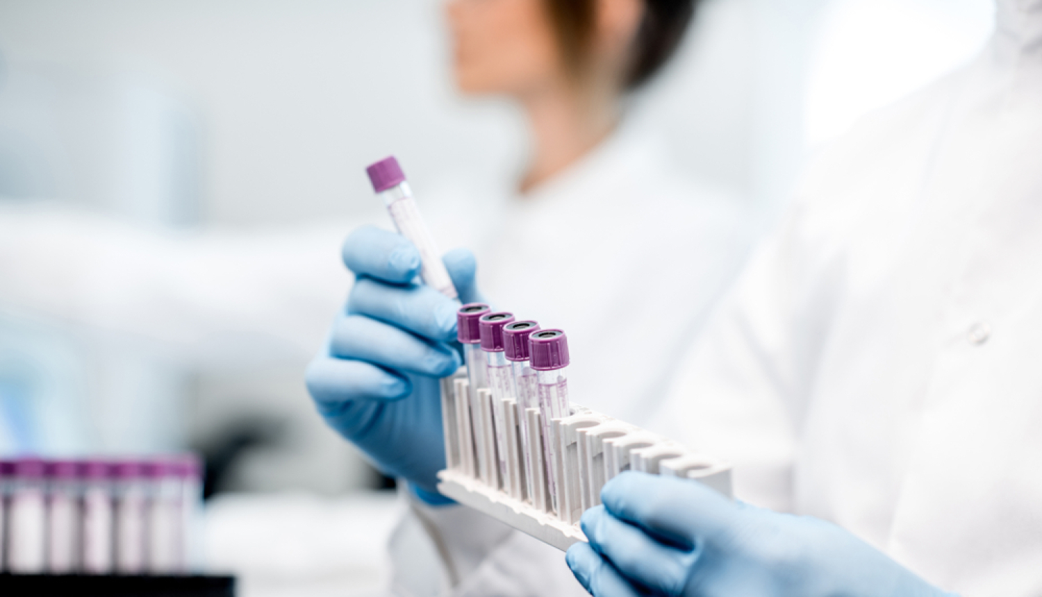 Medicīnas personāls tur rokās analīžu kolbiņas