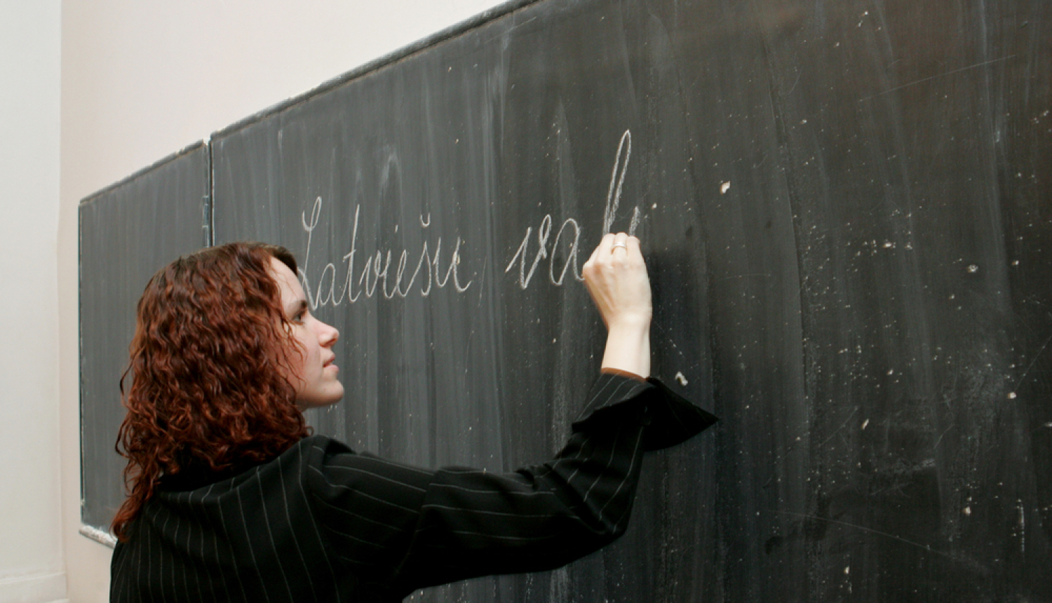 Sieviete raksta uz tāfeles latviešu valodā