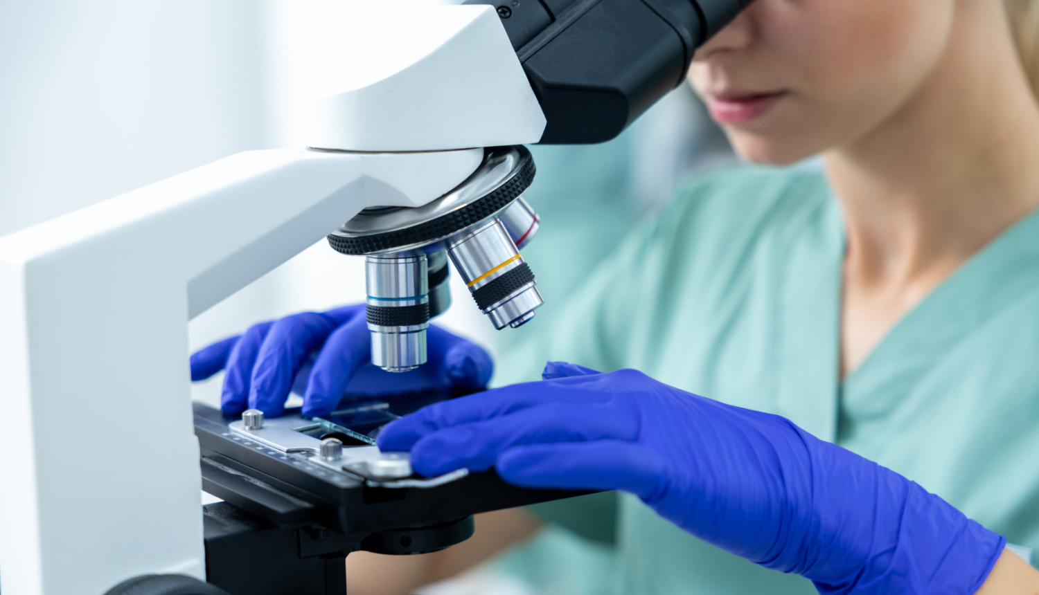 Sieviete aplūko paraugu mikroskopā