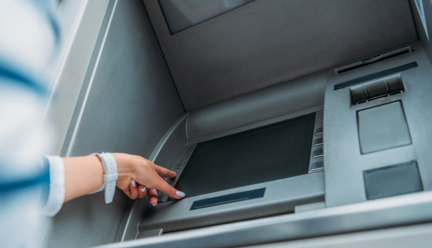 Bankomāts. Sieviete spiež pogas ekrānā. 