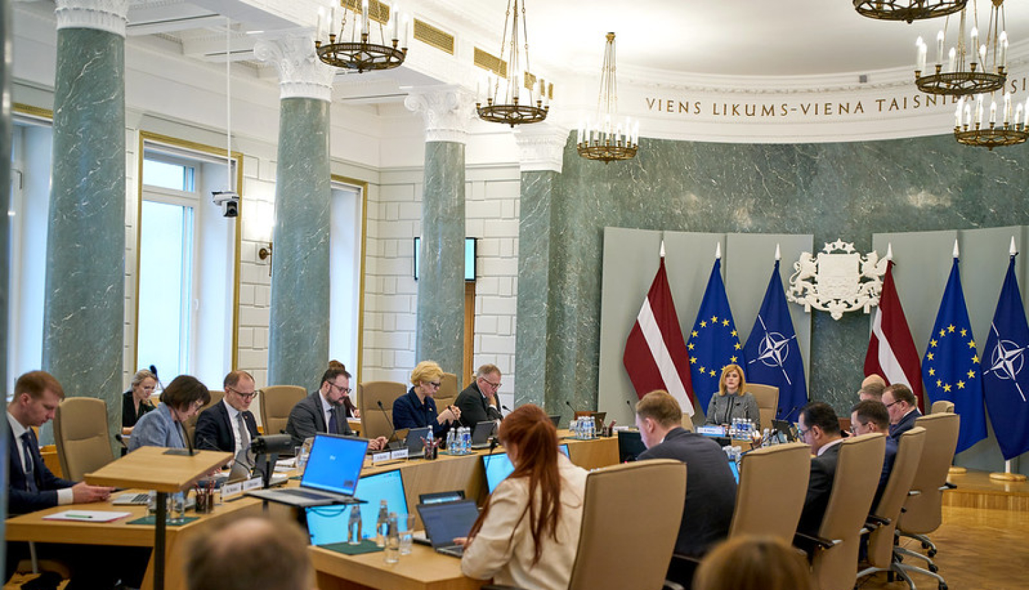 Ministri un Ministru prezidente sēž ap galdu MK sēžu zālē. Notiek MK sēde. 