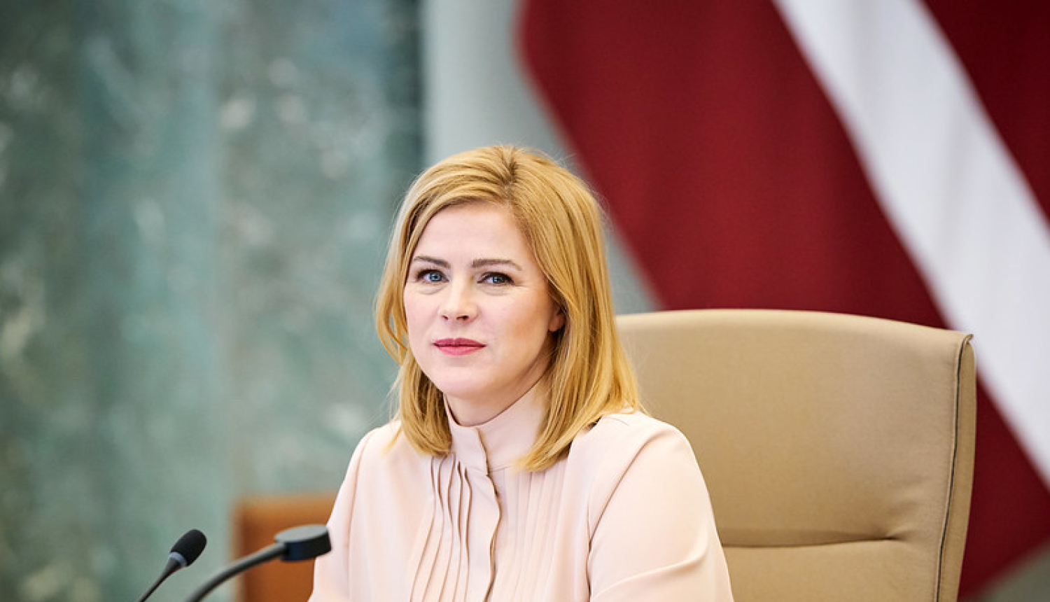 Ministru prezidente Evika Siliņa pie galda Ministru kabineta sēžu zālē. Fonā Latvijas karogs.