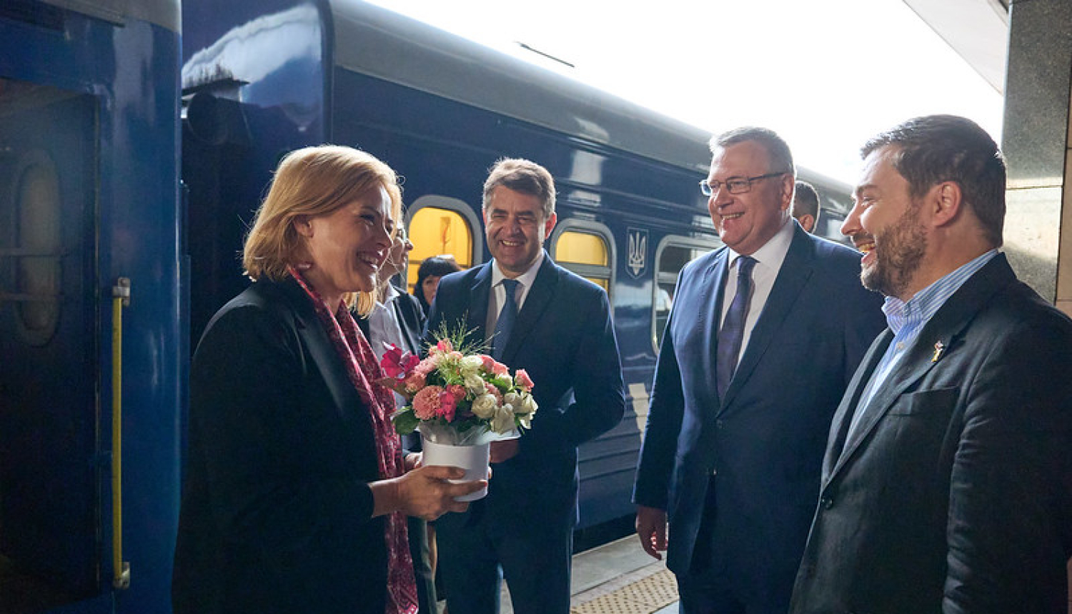 Ministru prezidente Evika Siliņa Kijivā. Ministru prezidenti sagaida amatpersonas.  Fonā vilciens. 