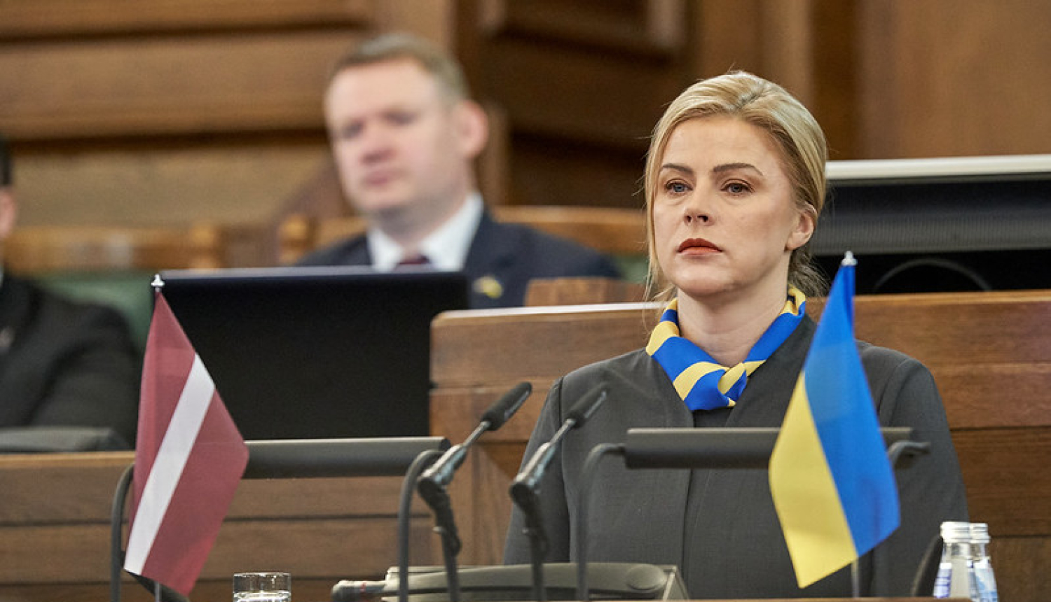 Ministru prezidente Evika Siliņa Saeimas sēdē. Uz tribīnes Ukrainas un Latvijas karogi. 