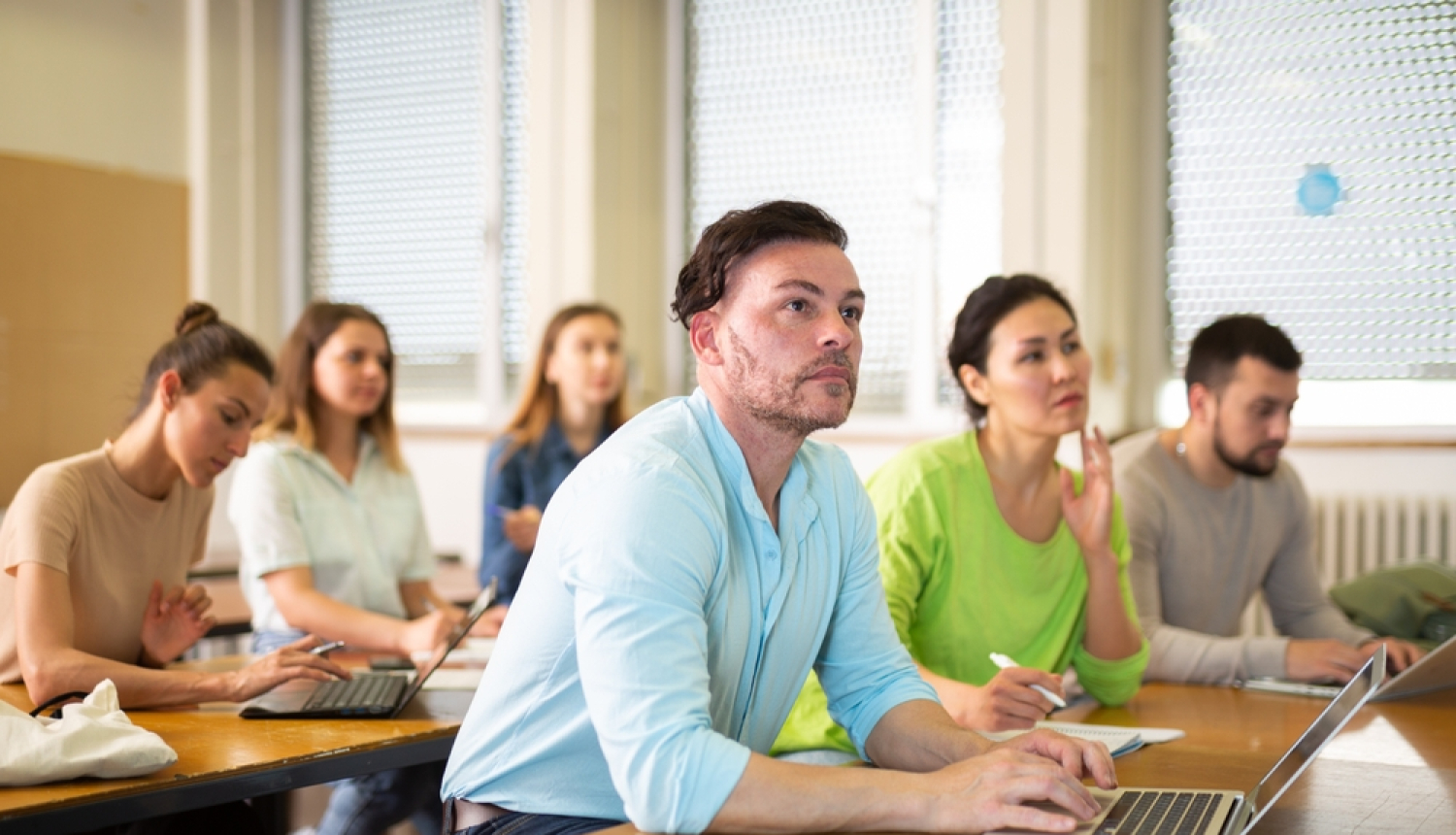 Pieaugušo izglītība - cilvēki mācību telpā ar datoriem. 