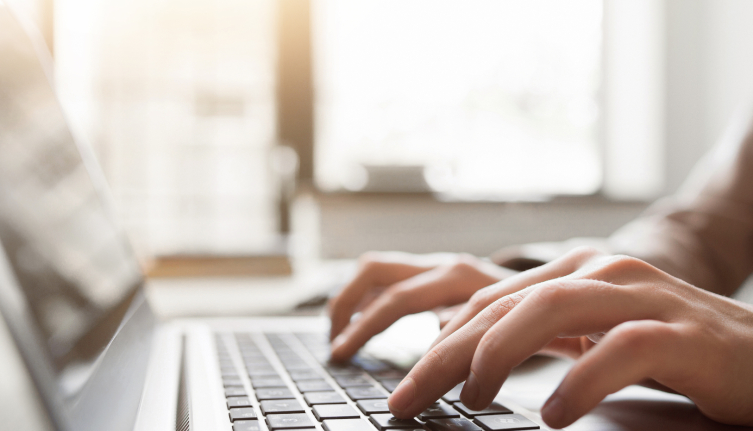 Cilvēka rokas tuvplānā, rakstot uz datora klaviatūras