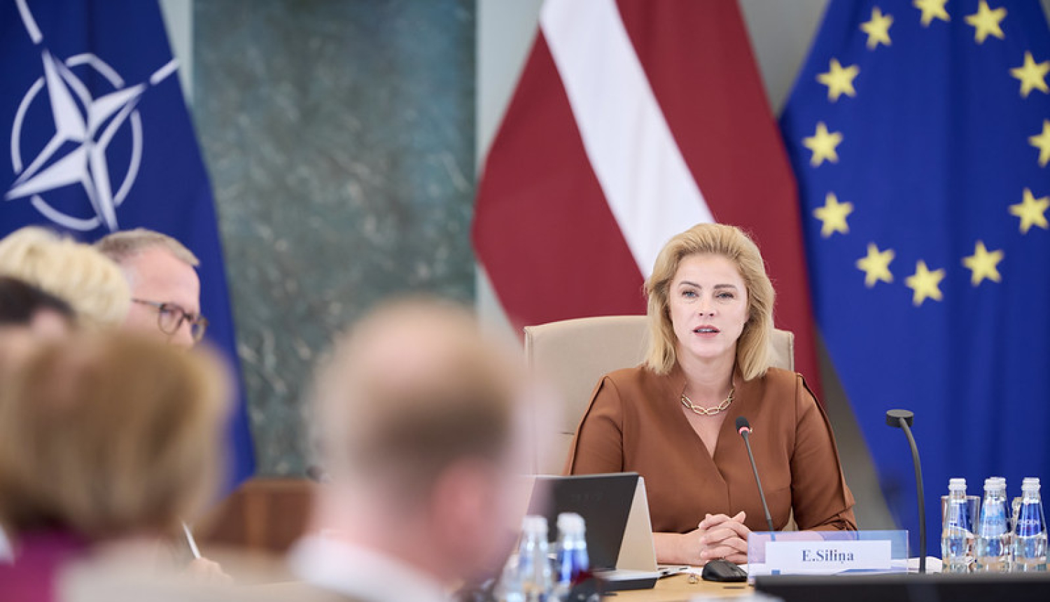 Ministru prezidente Evika Siliņa valdības sēžu zālē pie galda ar ministriem. 