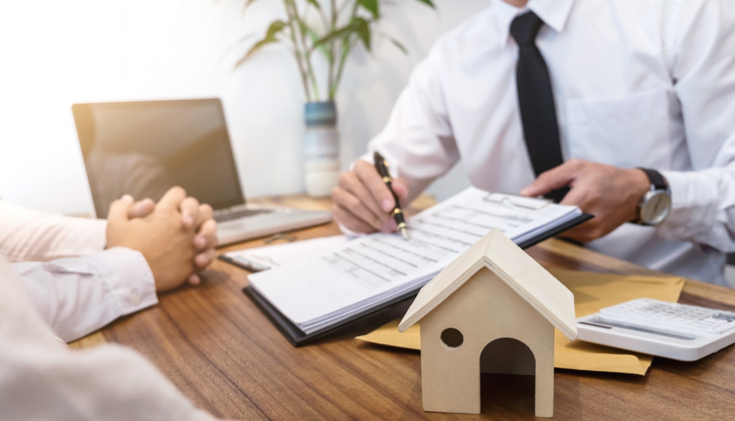 Bankas darbinieks pasniedz pārim dokumentus par hipotekāro kredītu mājas iegādei