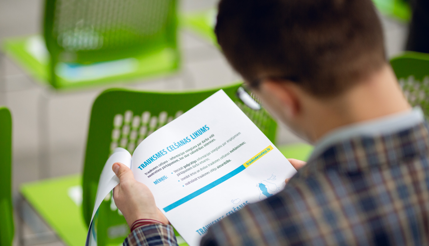 Foto: vīrietis tur rokā lapu, kur rakstīts "Trauksmes cēlēju likums"