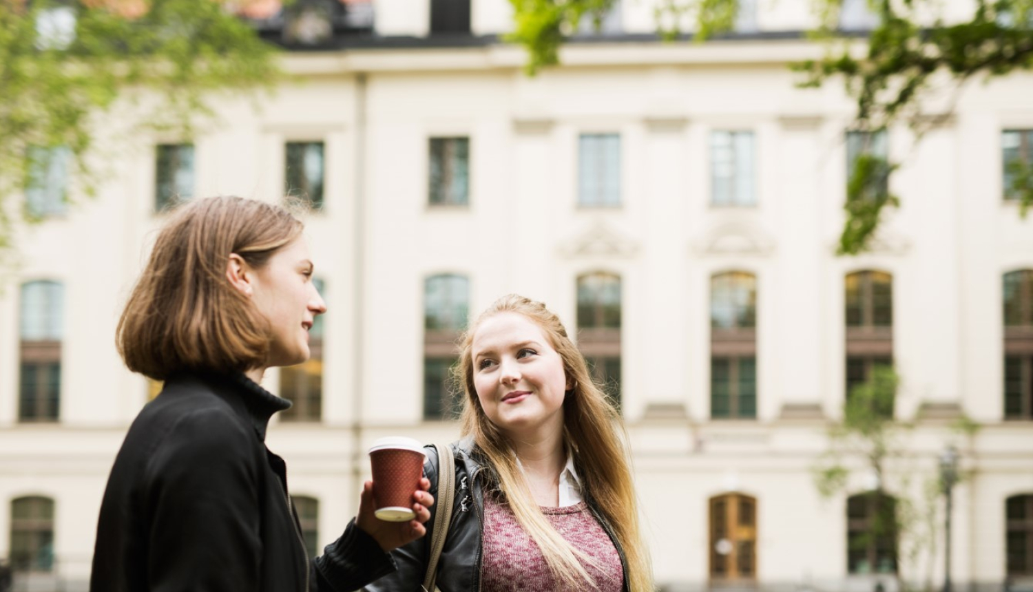 Divas jaunas sievietes, fonā mācību ēka