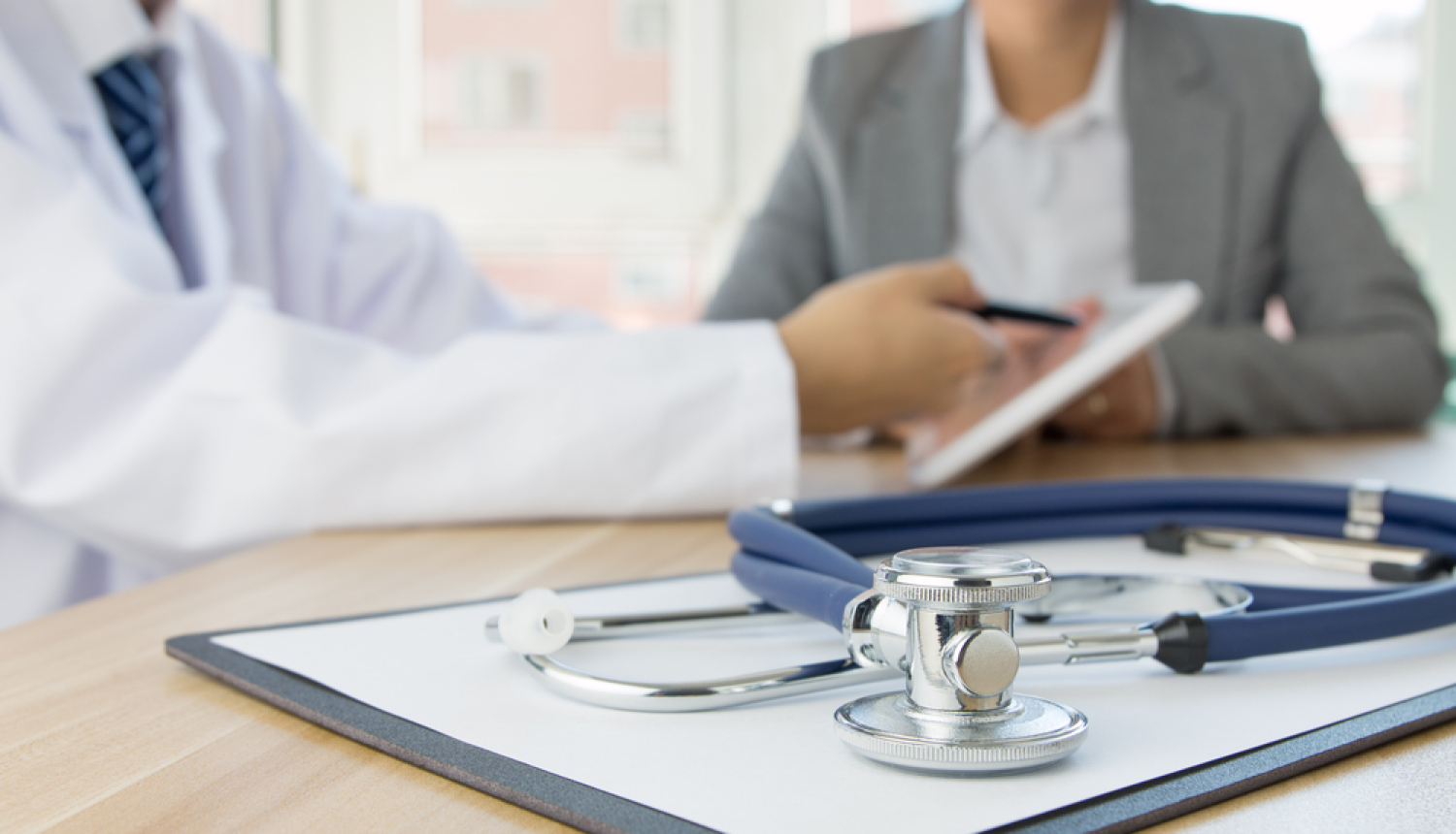 Ārsts un pacients. Uz galda stetoskops. 