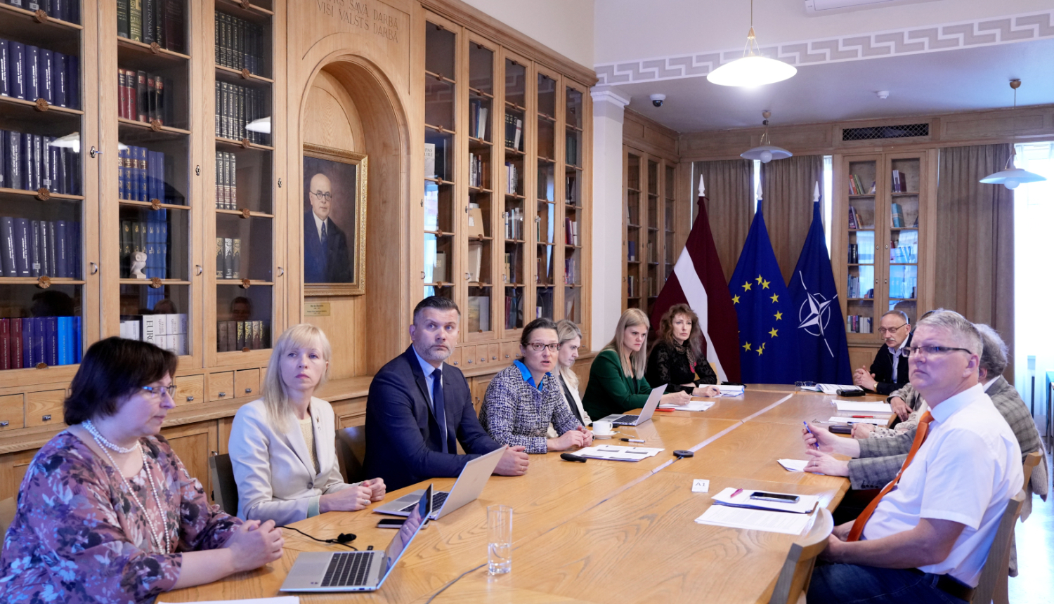 Semināra dalībnieki sēž pie galda Ministru kabineta bibliotēkā