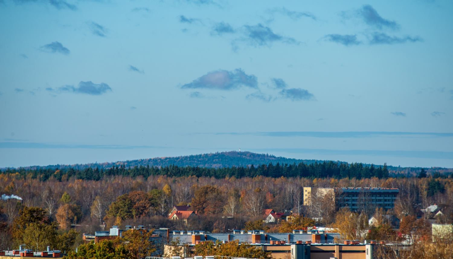 Skats uz pilsētu un tālumā esošu mežu un pakalnu
