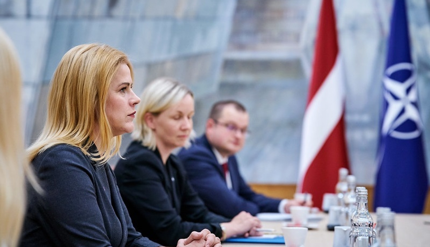 Ministru prezidente Evika Siliņa tikšanās laikā ar NATO amatpersonām. Fonā redzami Latvijas un NATO karogi
