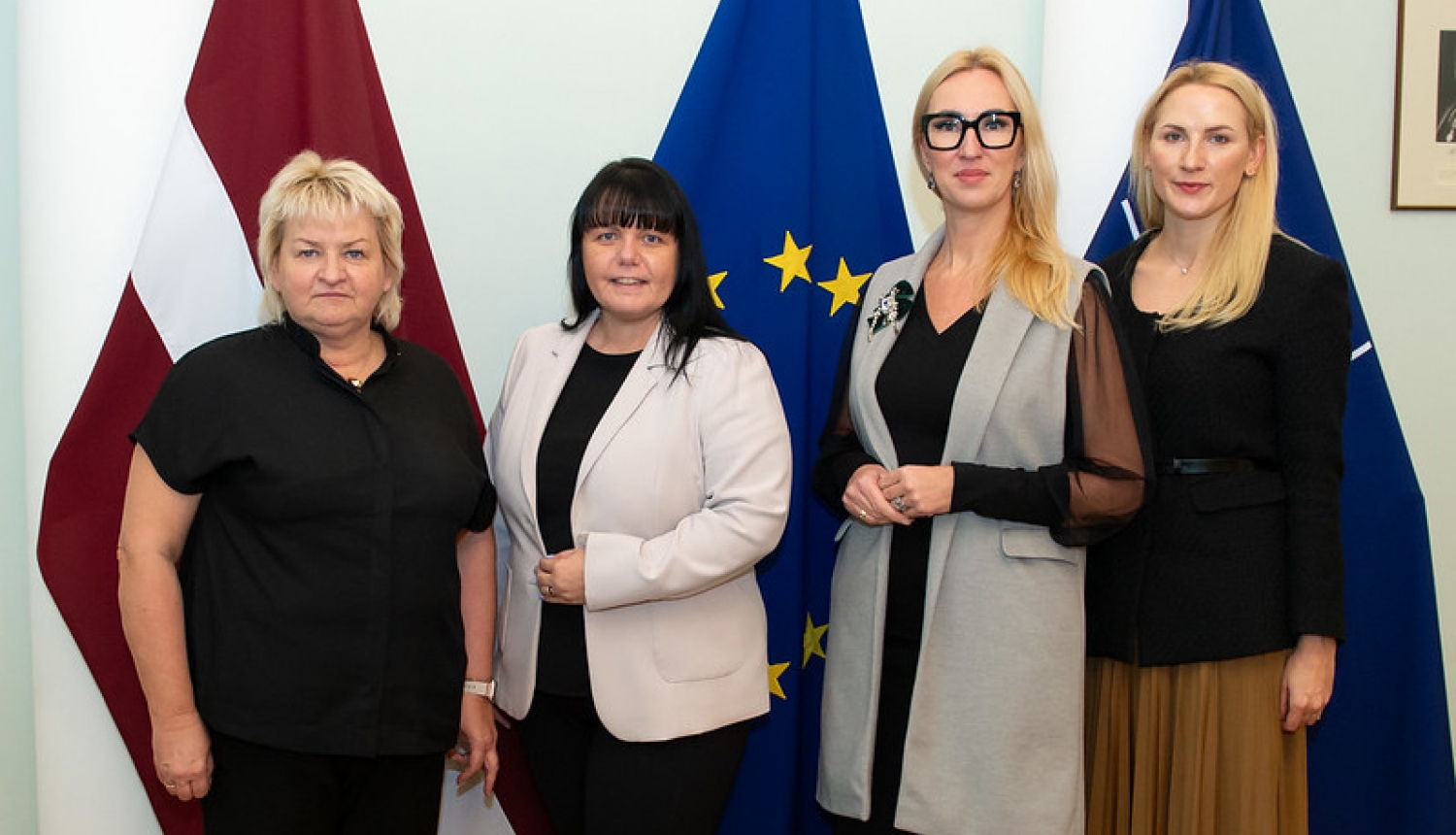 Tikšanās dalībnieces uz Latvijas, Eiropas Savienības un NATO karogu fona
