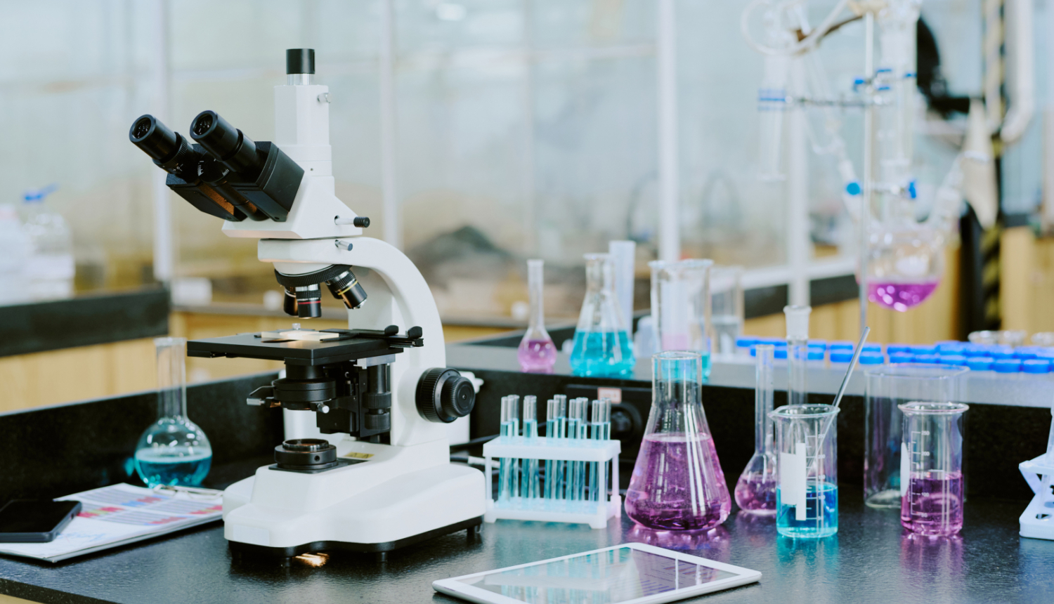 Mikroskops un mēģenes uz galda laboratorijā