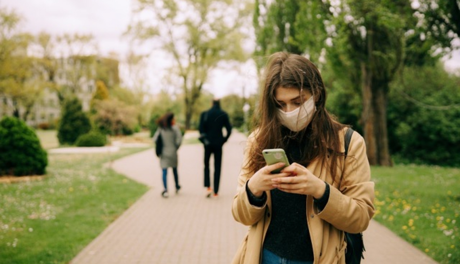 Meitene ar sejas masku skatās telefonā