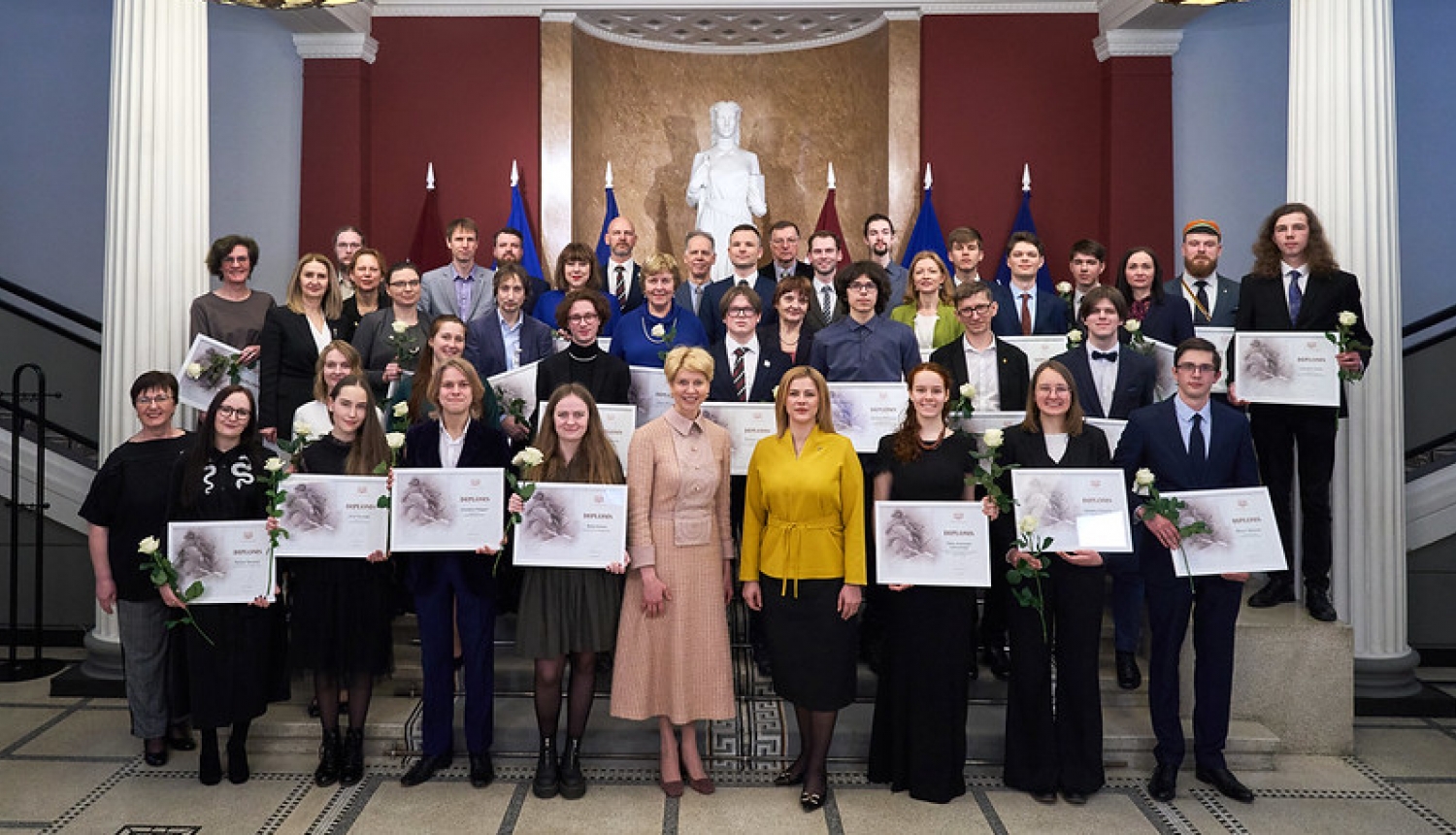 Kopibilde: centrā Izglītības un zinātnes ministre Anda Čakša un Ministru prezidente Evika Siliņa, apkārt Starptautisko olimpiāžu uzvarētāji, viņu pedagogi, konkursa EuroSkills uzvarētājs un prasmju pilnveidotājs, VISC  un VIAA pārstāvji. 